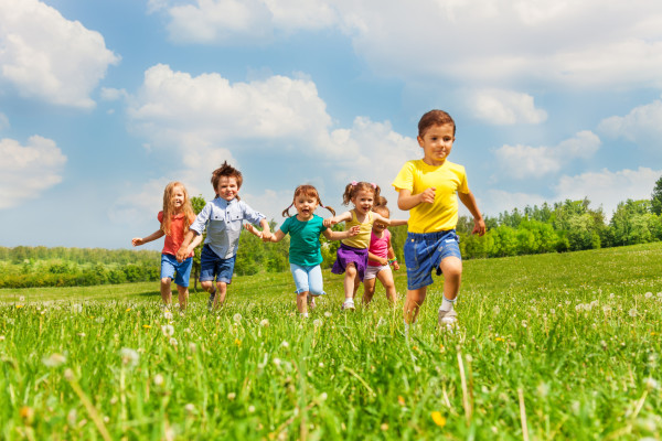 Running happy kids in green field during summer time