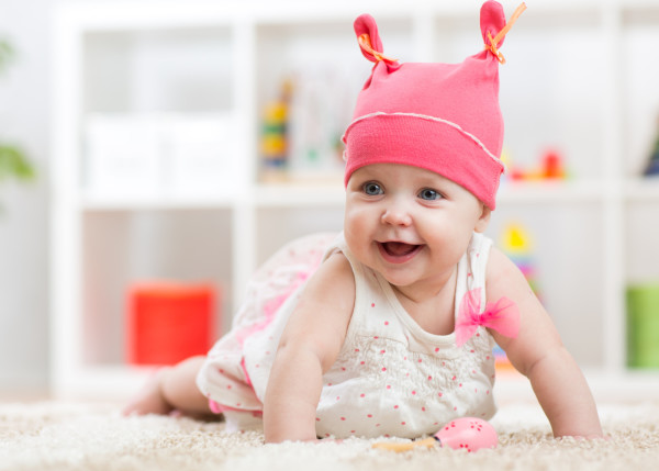 Smiling baby child crawling on nursery room floor