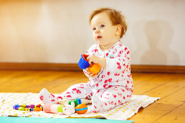 Portrait of cute infant girl playing with toy blocks at floor background.