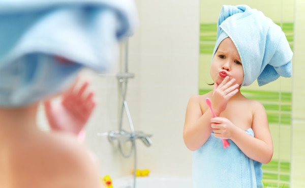 funny little girl cleans teeth with a toothbrush in the bathroom